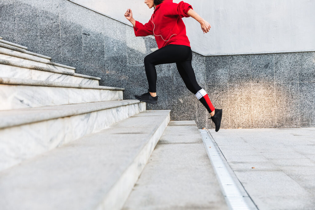 Person in red hoodie running up the stairs