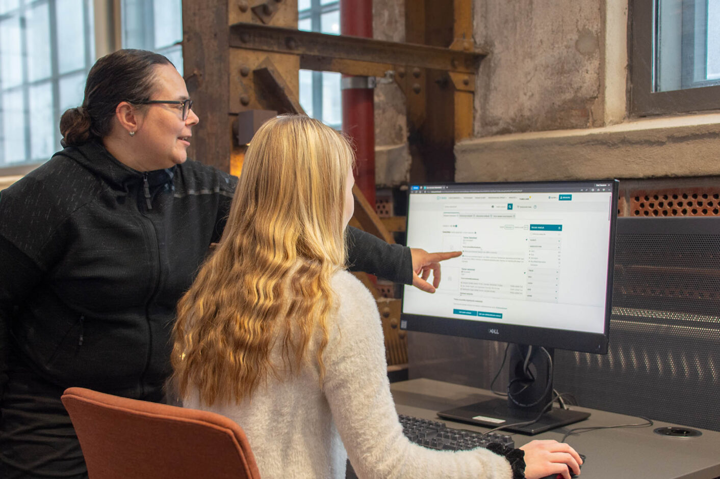 A librarian guides a person through the search for information on the computer.